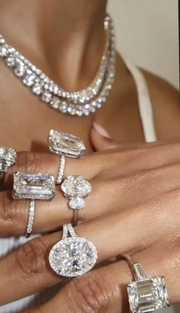 Model wearing diamond tennis necklaces and emerald, oval and halo diamond rings