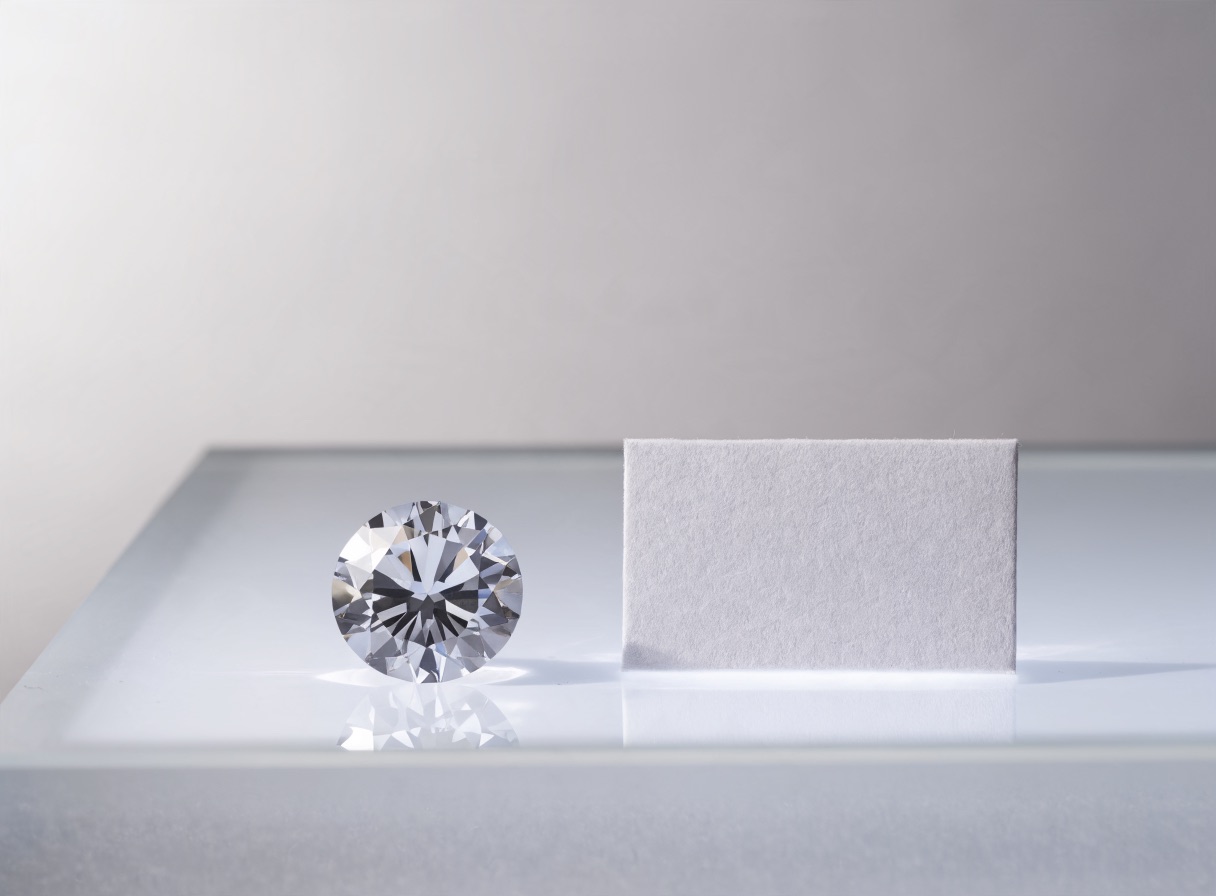 A loose polished diamond next to a blank grading report card on a light table