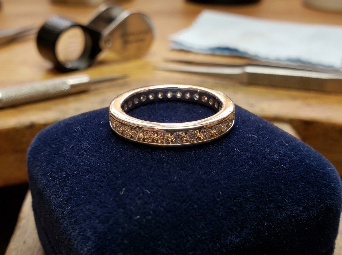 Finished channel-set wedding band with a continuous row of round melee diamonds on navy velvet