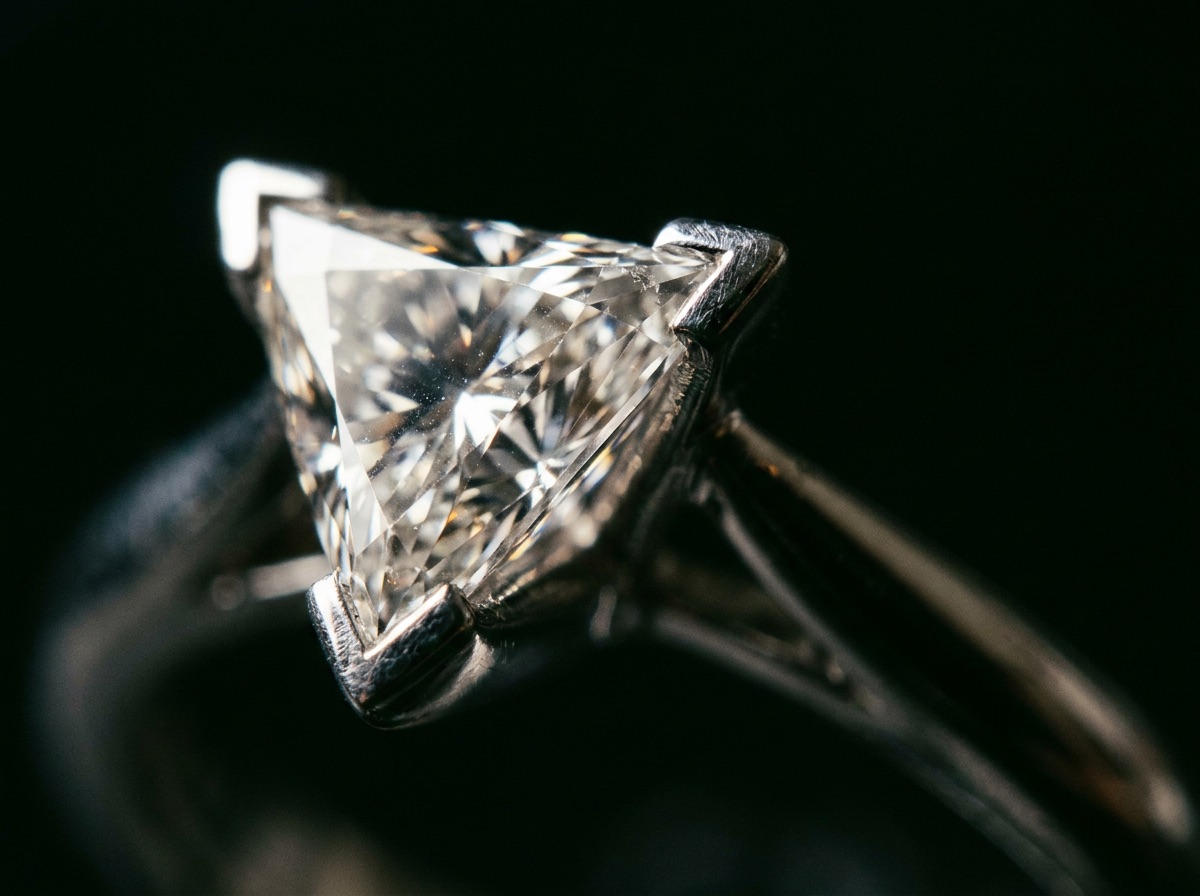 Matched pair of triangle cut diamonds with sharp step-cut corners on a cream linen backdrop